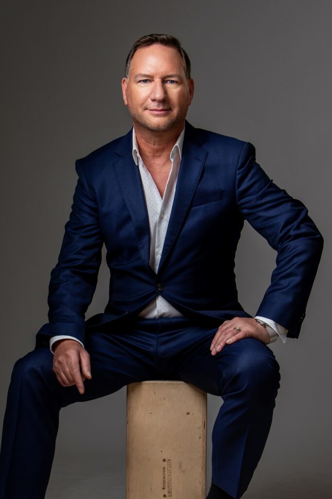 A man in a blue suit sitting on a wooden box.