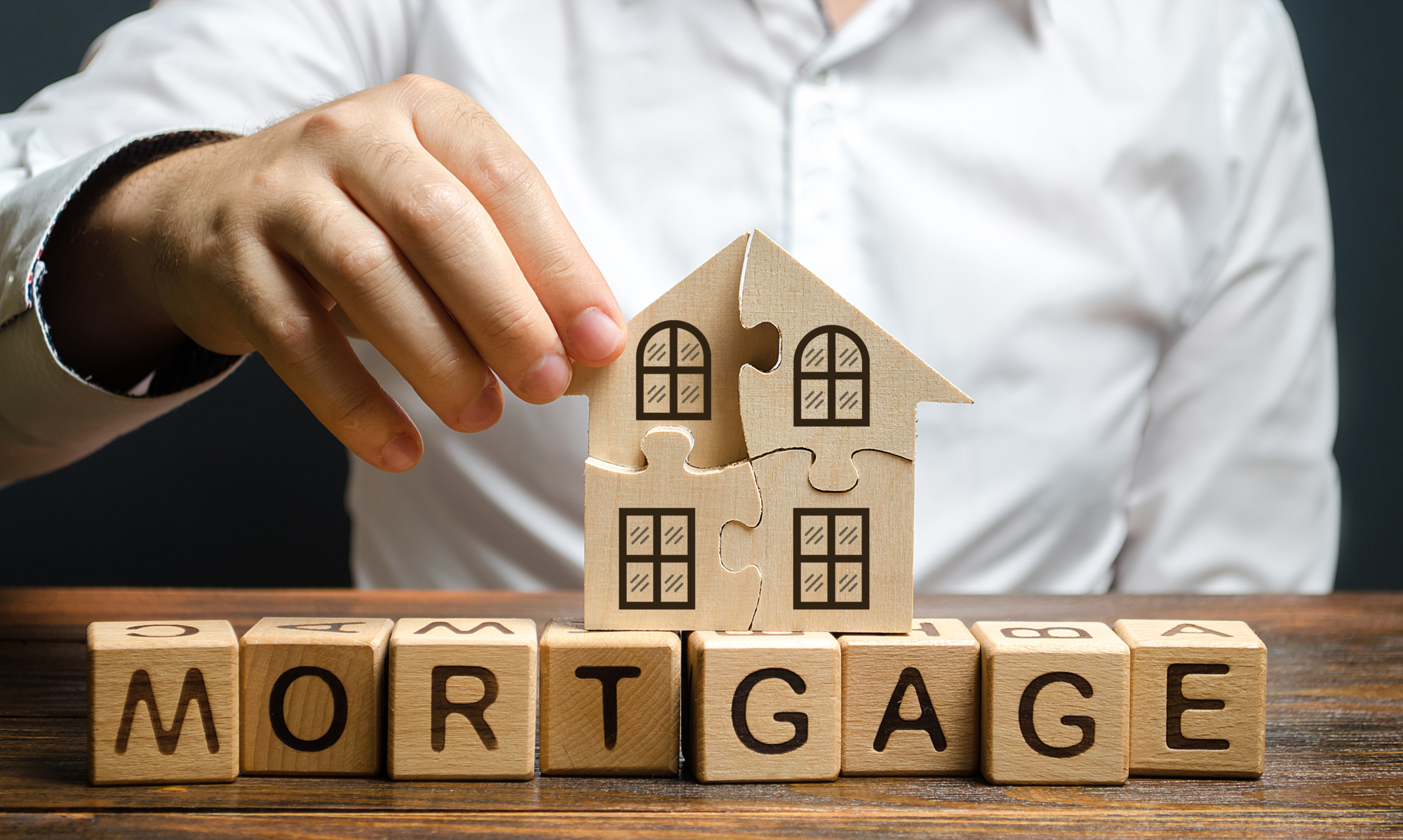 A man collects a house puzzle over the inscription Mortgage. Construction of your own residential building. Buying a home on credit loan, improvement of living conditions. Creating a family.
